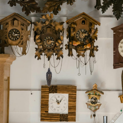Wall display of vintage-style cuckoo clocks with wooden design and intricate pendulum, showcasing decorative living room accents.
