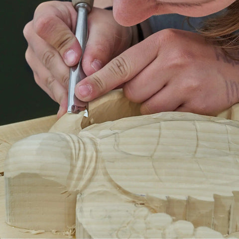 Person carving detailed design on basswood with chisel, showing technique and texture of 12 Pack Unfinished Basswood Carving Blocks Kit.