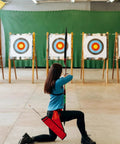 Person aiming at targets with Archery Target Paper Set For Backyard Practice And Hunting, indoor setup with target faces visible.