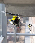120S2 RC Helicopter BNF With SAFE Technology flying indoors, showcasing lightweight carbon fiber airframe and durable polymers.