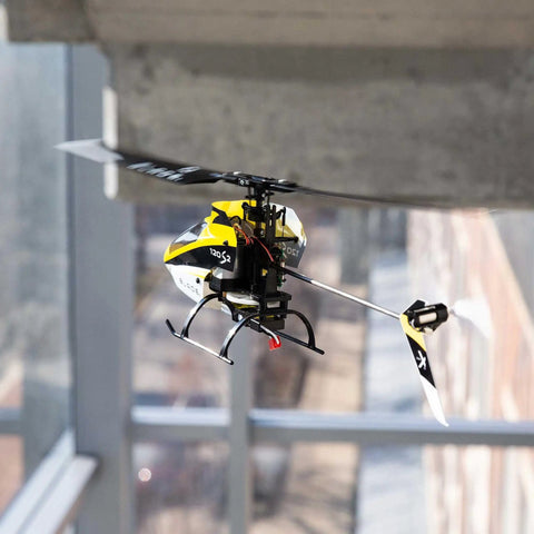 120S2 RC Helicopter BNF With SAFE Technology flying indoors, showcasing lightweight carbon fiber airframe and durable polymers.