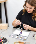Woman arranging beads on a Solid Felt Beading Mat Featuring Sweet Non Slip Flocking Independent Grids 14 X 11 Inch.