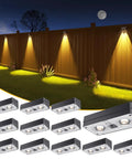 12 Pack Solar Fence Lights Slinging 50 Lumens Of Seriously Bright Glow Featuring Twelve Adjustable RGB Modes To Kick Up The Vibe On Your Patio Deck Or Backyard Railing Weatherproof Outdoor Lighting Solution Built To Last, shown on a fence at night.