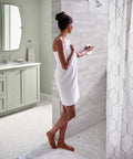 Person in bathroom using Gibson Chrome Posi Temp Shower Trim With Pressure Balancing Eco Performance, tiled shower visible