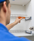 Person installing heavy duty glass brackets set with suction cups and fixing screws in a cabinet using a screwdriver.