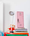 Pink Miniature Metal Locker With Secure Diary Lock And Two Keys For Hella Cute Desk Setup Soft Padded Base on a desk with books and a lamp.