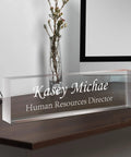 Custom Engraved Desk Name Plate In Acrylic on wooden desk with "Kasey Michael, Human Resources Director" text, modern office decor
