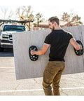 Man using Grabo Nemo Electric Vacuum Suction Cup Lifter to carry large stone panel effortlessly outdoors.