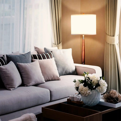 Lucas LED Floor Lamp With Drum Shade And Warm Wood Finish beside a sofa in living room.