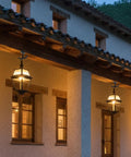 Outdoor lanterns hanging on rustic building facade with warm lights, showcasing evening ambiance and architectural design.
