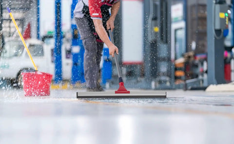 Heavy Duty Floor Squeegee With Extendable Telescopic Handle From 30 To 57 Inches 24 Inch Wide Built For Concrete Tiles Garage Deck Bathroom And Window Cleaning Rust Resistant Aluminum Stainless Steel Pole being used to clean a wet garage floor.