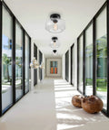 Heavy Duty Industrial Semi Flush Mount Ceiling Light With Tough Matte Black Frame And Authentic Seeded Glass Cover For A Big Time Modern Vintage Lighting Glow in a bright hallway.