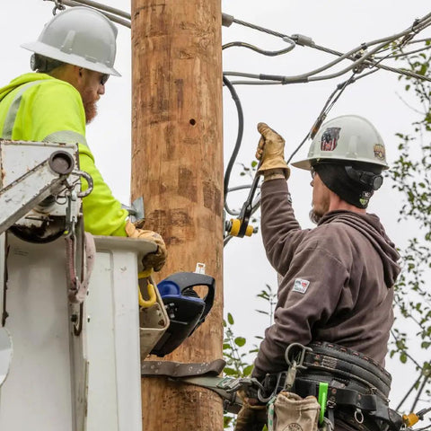 Utility workers using Six In One Lineman's Ratcheting Wrench With Bolt Through Design And Bright Yellow Socket on pole hardware.