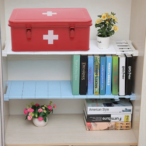 Red metal first aid kit box with white cross emblem and two latches on a white shelf.