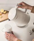Person pouring water from Soho 1-Liter Double Wall Electric Kettle With Stainless Steel Interior One-Touch Boil into white mug