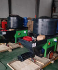 Two Portable Cement Sand Mortar Plastering Sprayer Pumps on pallets in a warehouse setting, designed for wall stucco coating.