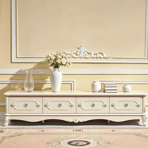 Elegant cream-colored cabinet with decorative drawers and crystal knobs, styled with floral arrangement and vases.