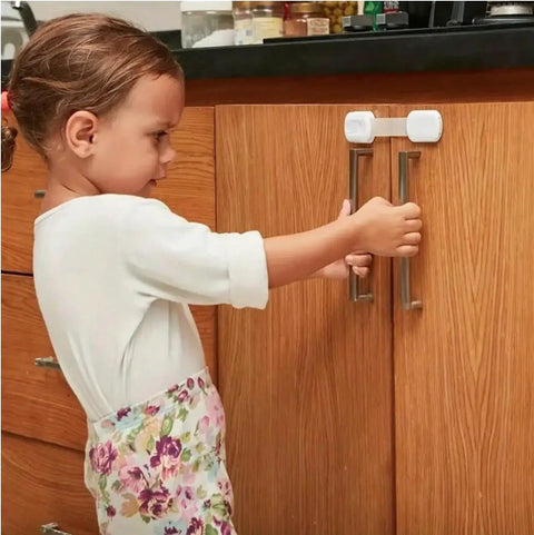 Child interacting with cabinet secured by Adhesive Baby Proof Straps Locks Pack Of 10 No Drilling Required For Cabinets Drawers Fridge Dishwasher.