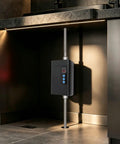 Bulletproof 3000W Tankless Water Heater With LCD Screen, mounted in kitchen, showcases black unit with digital display and pipes.