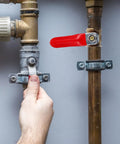 Hand operating red handle of Kickass 2Pcs Copper Ball Valve 6MM Fittings, showcasing garden piping system adjustment.