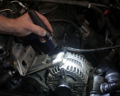 Person using Strion HL 615 Lumen Rechargeable Pro Flashlight Without Charger in engine bay highlighting alternator
