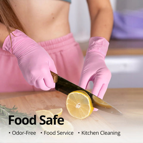 Pink nitrile disposable gloves worn while slicing a lemon on a wooden cutting board