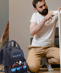 Man assembling furniture with Super Tough Rugged Heavy Duty Tool Bag Backpack beside him, showcasing massive storage 49 pockets.