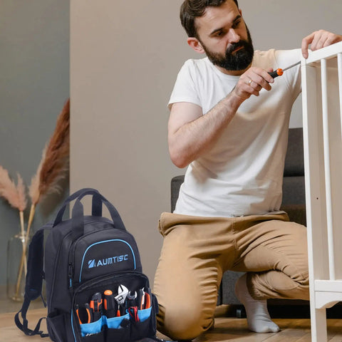 Man assembling furniture with Super Tough Rugged Heavy Duty Tool Bag Backpack beside him, showcasing massive storage 49 pockets.