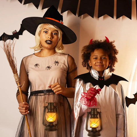 Two children dressed in Halloween costumes holding Outdoor Solar Lanterns With Flicker Flame LED, adding a warm glow.