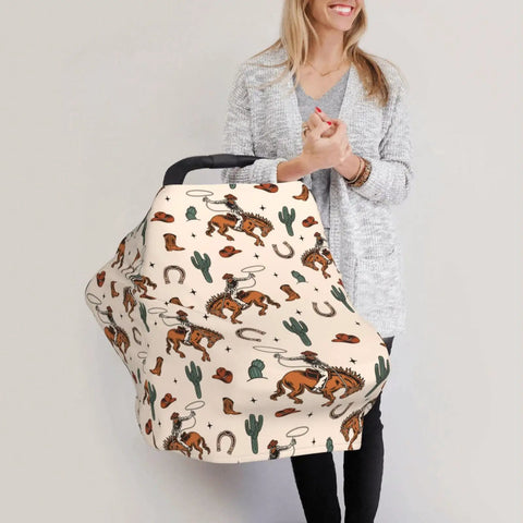 All In One Baby Car Seat Canopy And Nursing Cover with cowboy print, held by woman, breathable multi use shield for car seats