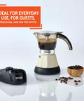 Dang Compact Two Cup Electric Espresso Maker With Cool Touch Handle Brews rich smooth coffee on countertop with coffee beans.
