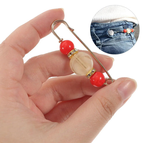 Hand holding a 12 Piece Heavy Duty Alloy Waist Adjustment Pin with decorative beads for securing baggy jeans.