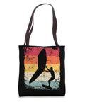 Retro Wing Foil Tote Bag For Wingsurfing And Wingboarding Men Vintage Style Gear For Surfers Who Live The Wing Foil Life And Colorful Tote Makes A Bold Accessory Statement with a colorful silhouette of a man wingsurfing against a sunset background.