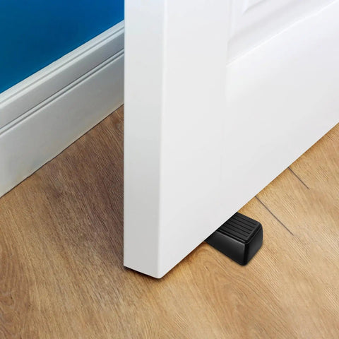Four Pack Built Tough Heavy Duty Door Stoppers Zinc Alloy Wall Protector With Non Slip Surface Wedge holding a door open on wooden floor.