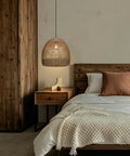WALMHEIM 15.7" Boho Rattan Pendant Light Fixture over a wooden bedside table in a rustic bedroom setting.
