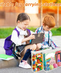 Two children using a tablet with three clear storage boxes containing toys and stationery on the ground, outdoors.