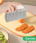 Stainless steel crinkle cutter with white handle, slicing carrots into wavy fries on a cutting board.