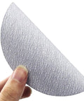 Grab This Awesome 100 Piece Set Of 5 Inch Wet Dry Sanding Discs With Grit From 60 To 1000 For Serious Polishing And Grinding Jobs Without Wasting Time Or Clogging Up Your Gear So You Can Get That Smooth Finish Fast. Hand holding a 5 inch wet dry sanding disc showing grit surface.