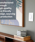 Slick Graphite LED Dimmer Switch Bringing Foolproof Three Way Rocker Action With Flat Out Zero Flicker Brightness Up To 150 Watts mounted next to framed artwork.