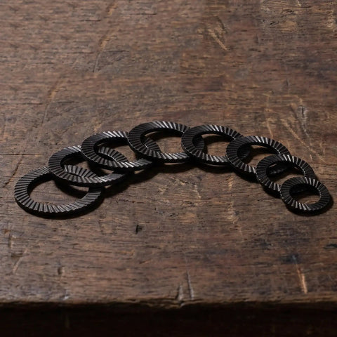 72 Piece Set Double Tooth Lock Washers Black Ironclad Grip 65mn Steel showing multiple washers on wooden surface.