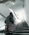 Person carrying 2Go 2 Tool Container For On The Go Gear Organization, durable compact storage, ascending stairs, workplace setting.