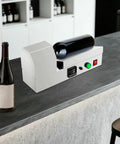 Compact Electric Heat Shrinking Machine For Pvc Bottle Sleeves And Wine Caps on a countertop with a wine bottle.