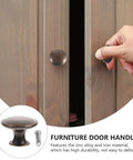 Hand using 12 Pack Round Antique Brass Cabinet Pulls Single Hole Small Flat Head Metal Drawer Handles For Kitchen And Bath Cabinets Replacement Retro Furniture Knobs Hardware on a wooden cabinet.