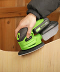 Garage Shop Ready Compact Detail Sander With 1.1A Motor Delivers 14,000 OPM sanding a wooden edge, includes dust bag and soft grip handle.