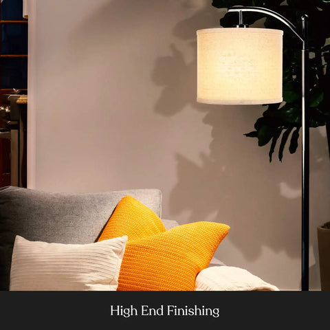 Arc Shaped LED Floor Lamp With Hanging Shade for Living Rooms and Offices next to a grey sofa with orange cushions.