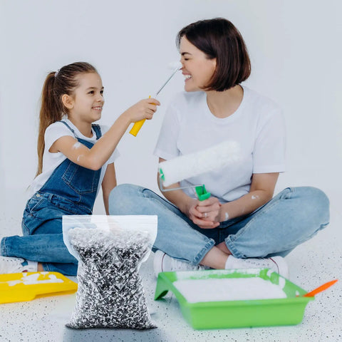 Mother and daughter with One Pack 2.8 Kg Decorative Epoxy Color Flakes DIY Friendly For Garage Floors And Concrete Coatings Blended Paint Chips For Walls Interiors Exteriors And Basements In Black White Gray Two To Four Millimeters, sitting on a floor with painting tools.