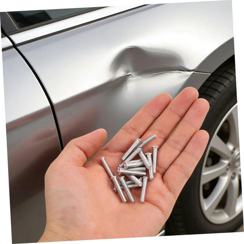 Hand holding 15 silver metal panel pulling studs for auto body work near a dented car door