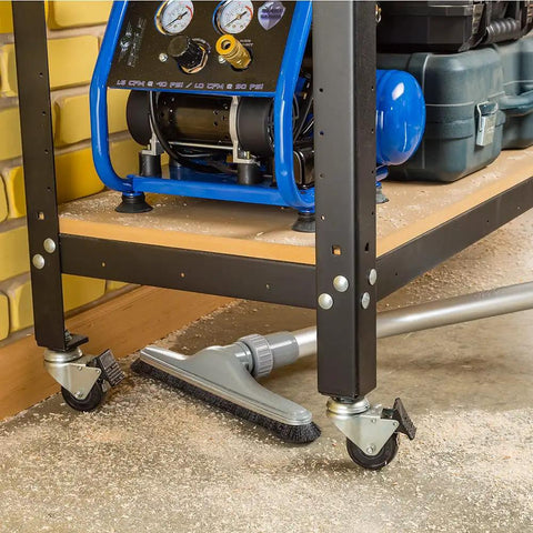 Heavy Duty Shop Vacuum Floor Sweep Attachment With Flexible Swivel Head And Angled Neck Designed To Scoop Sawdust And Floor Grit Under Workbenches on a workshop floor.
