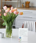 Floral card from the 100 Piece Floral Blank Note Cards Set, 4 by 6 Inches, on a table with tulips in a vase.