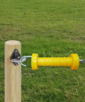 High Visibility Electric Fence Gate Handle Kit with one yellow handle attached to a wooden post in a field